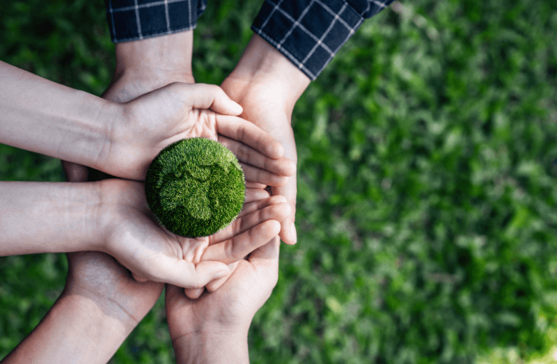 an image of hands holding an orb of SYNLawn artificial turf that looks like the earth