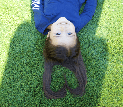 image of a girl laying on SYNLawn artificial turf with her hair making a heart shape