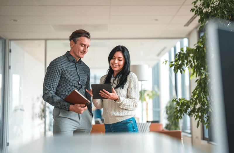 Two people in an office looking at a tablet